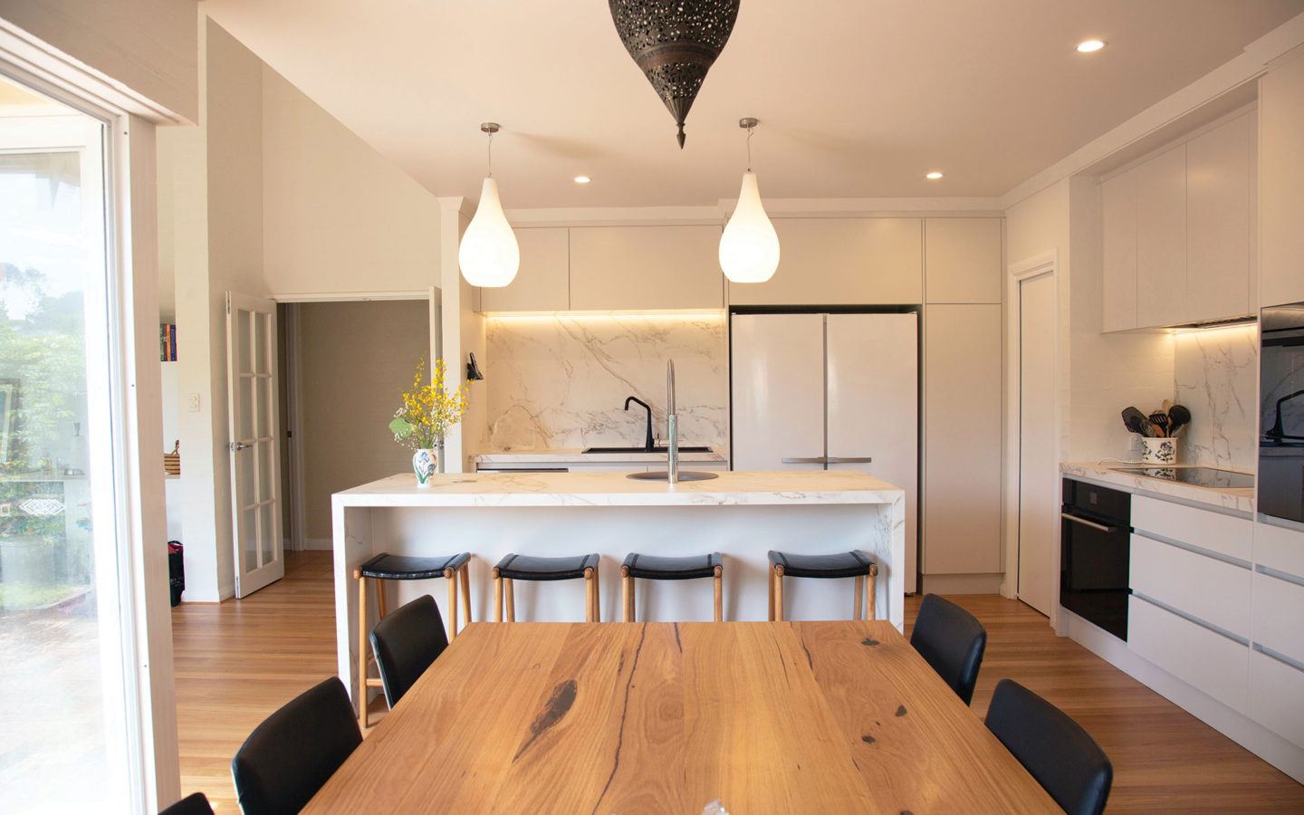 a kitchen island behind a large wooden dining table