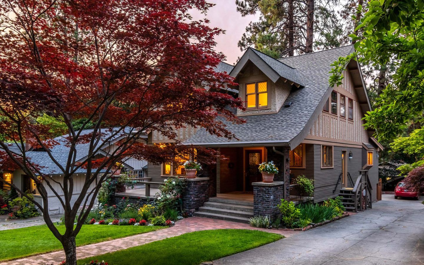 exterior photo of a house with a large maple tree infront