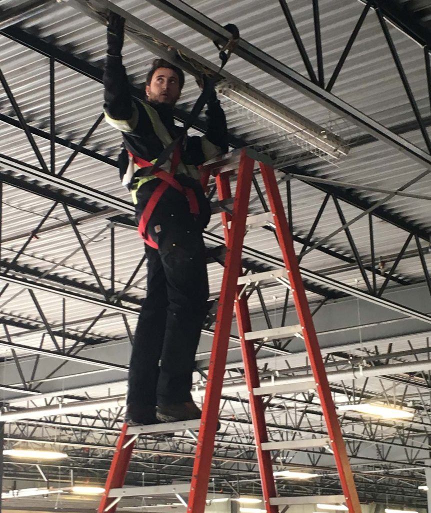 a man in safety gear standing on a red ladder