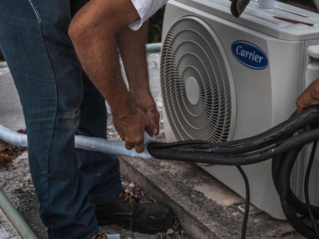 a man installing an air conditioning unit outside of a house