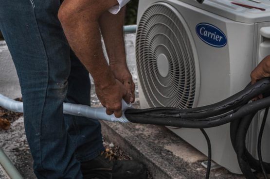 a man installing an air conditioning unit outside of a house